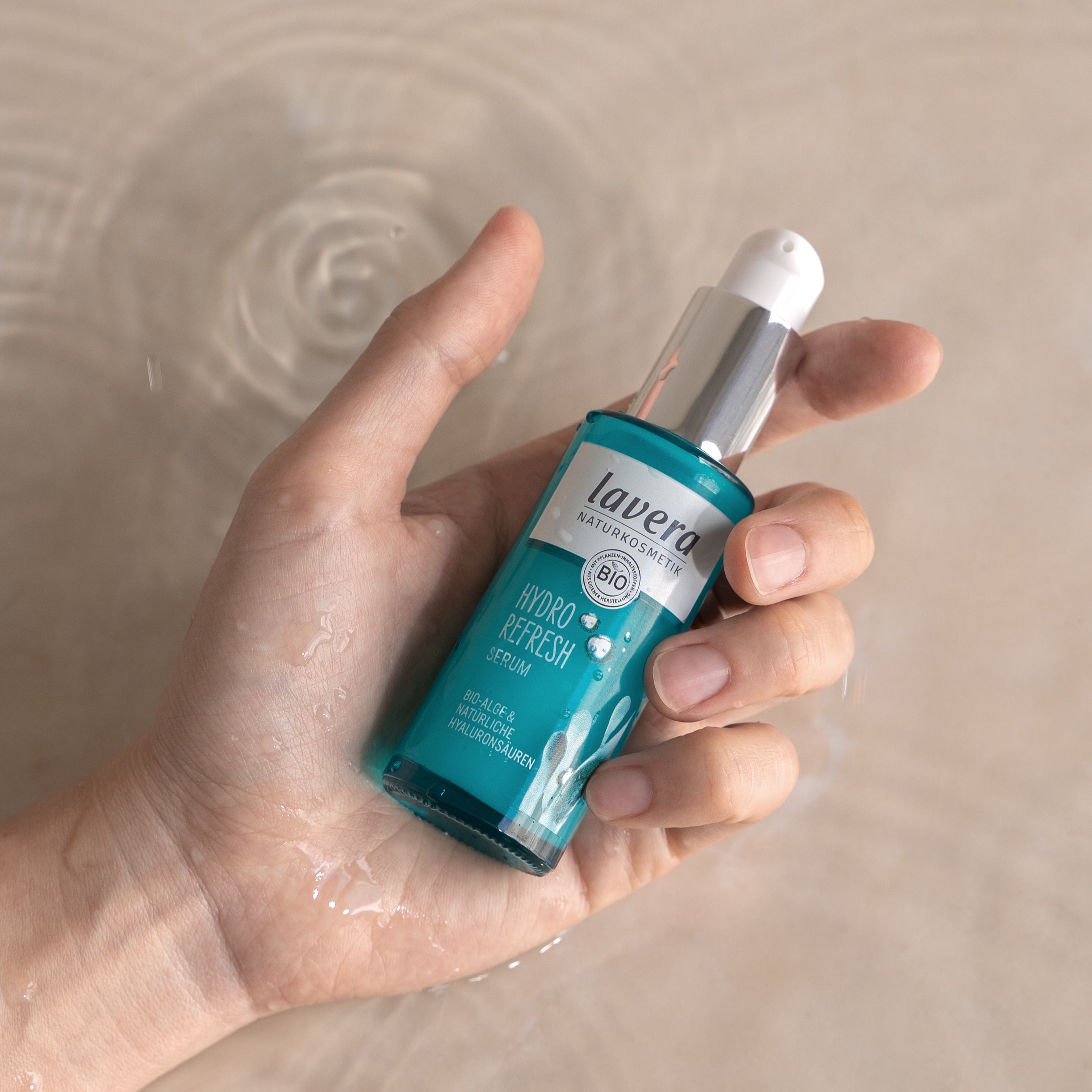 Hand hält lavera Hydro Refresh Serum über einer Wasseroberfläche.