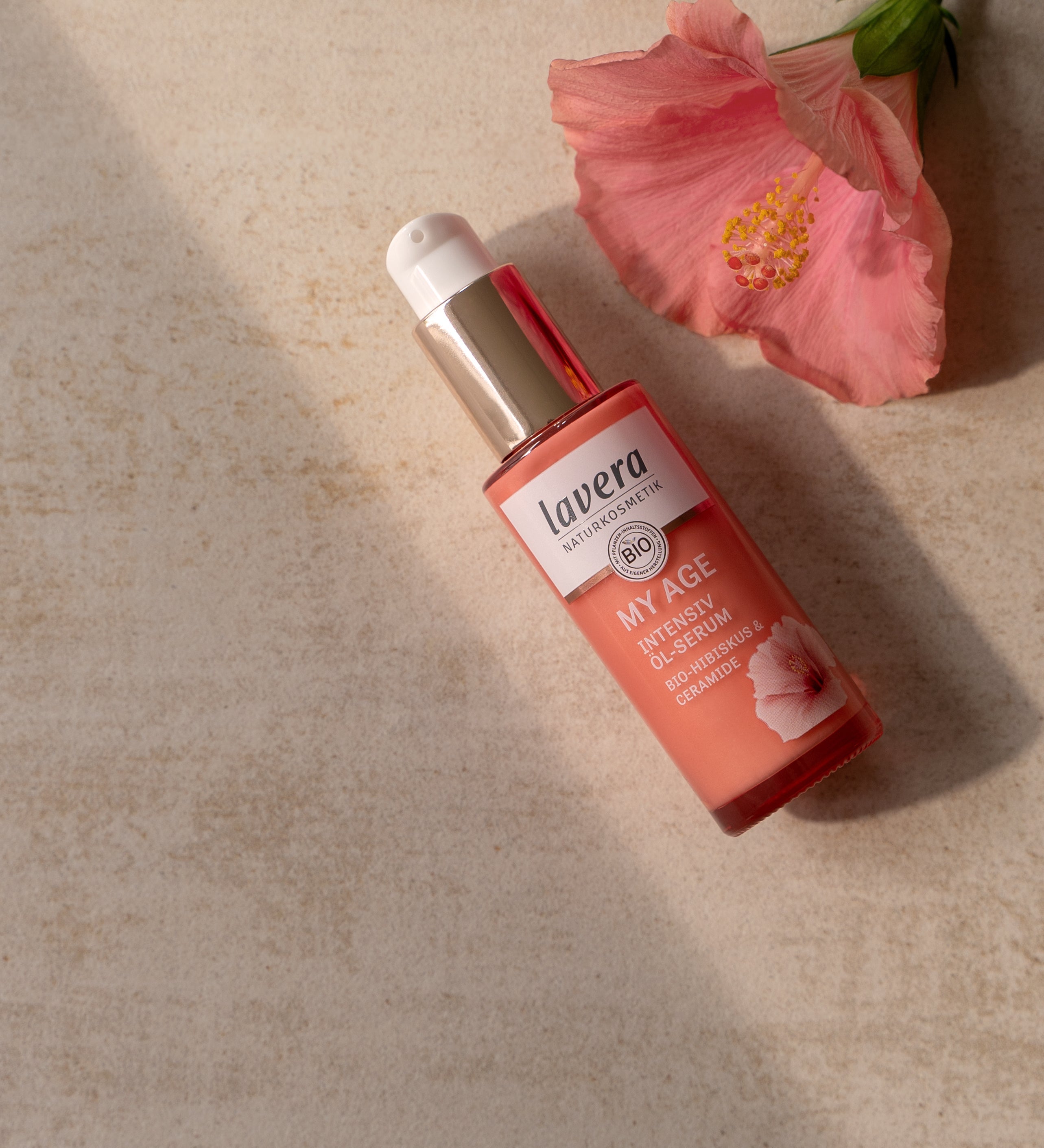 lavera My Age Intensiv Öl-Serum mit Hibiskusblüte auf hellem Untergrund.