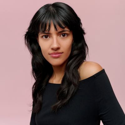 Porträt einer Frau mit schwarzem Haar und Pony vor rosa Hintergrund