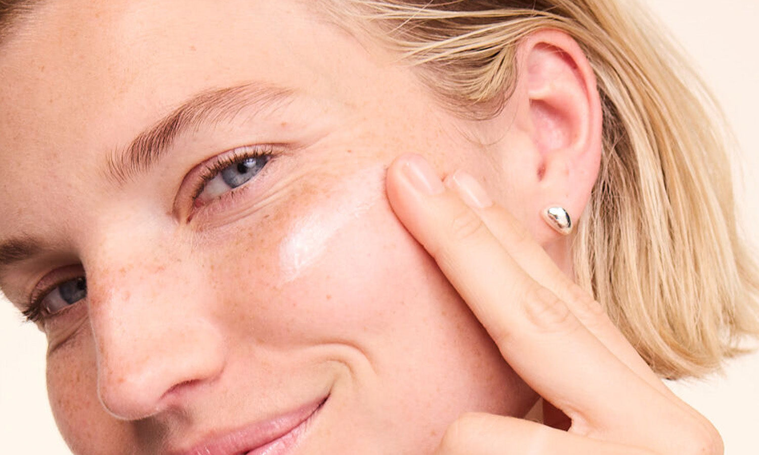 Nahaufnahme: Frau trägt Gesichtscreme auf die Wange auf