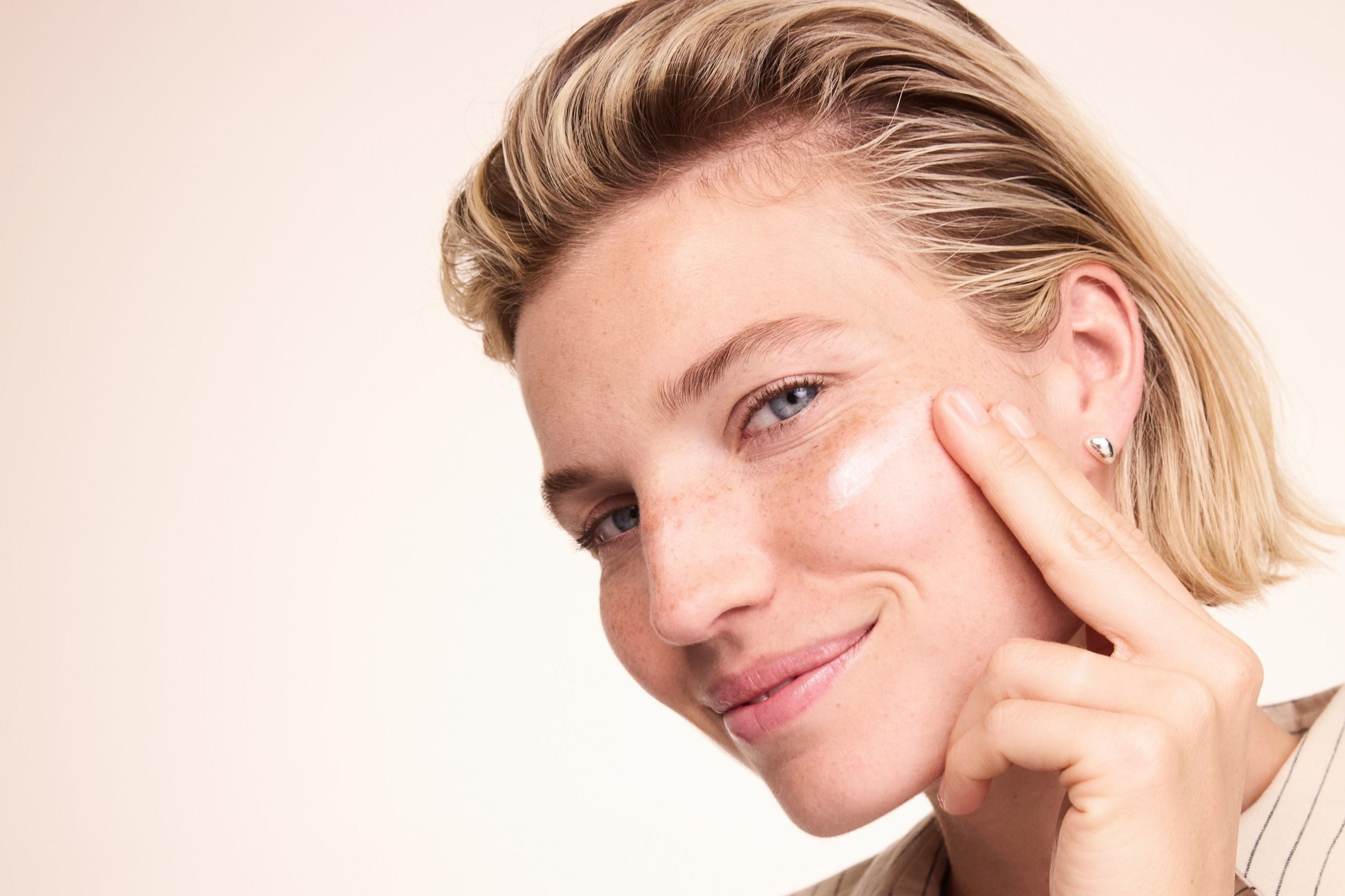 Frau trägt die Creme auf die Wange auf