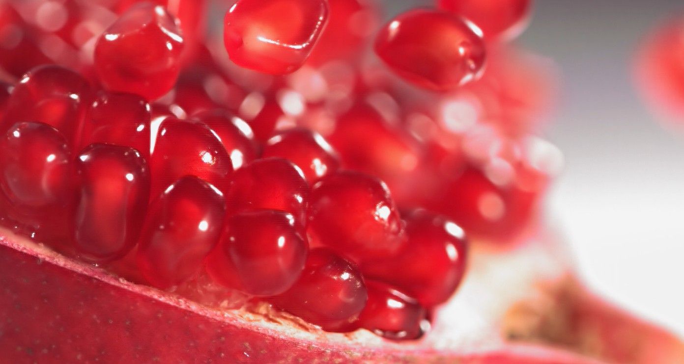 Nahaufnahme von glänzenden roten Granatapfelkernen in einer geöffneten Frucht.
