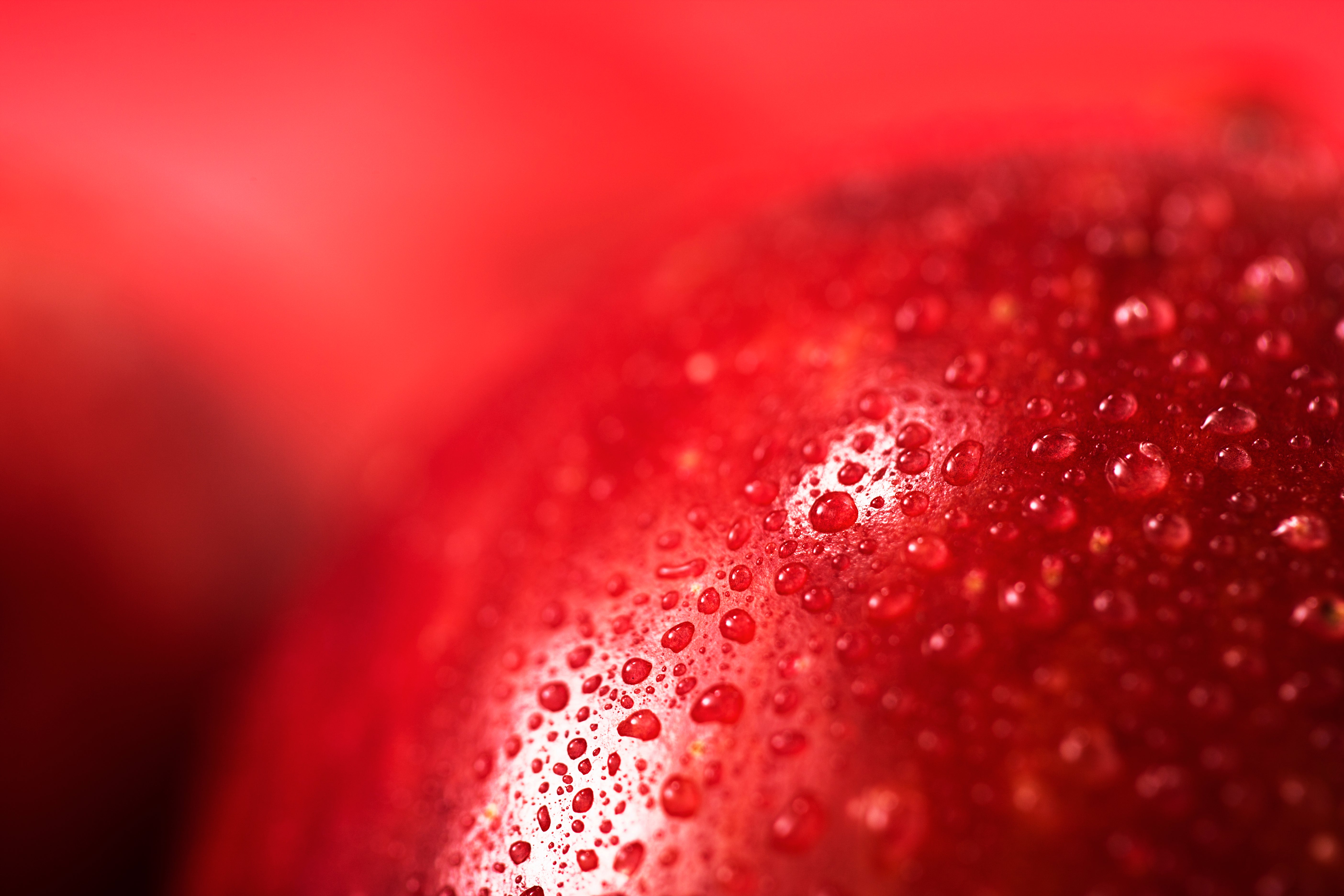rote Apfeloberfläche mit Wasserstopfen und rotem Hintergrund