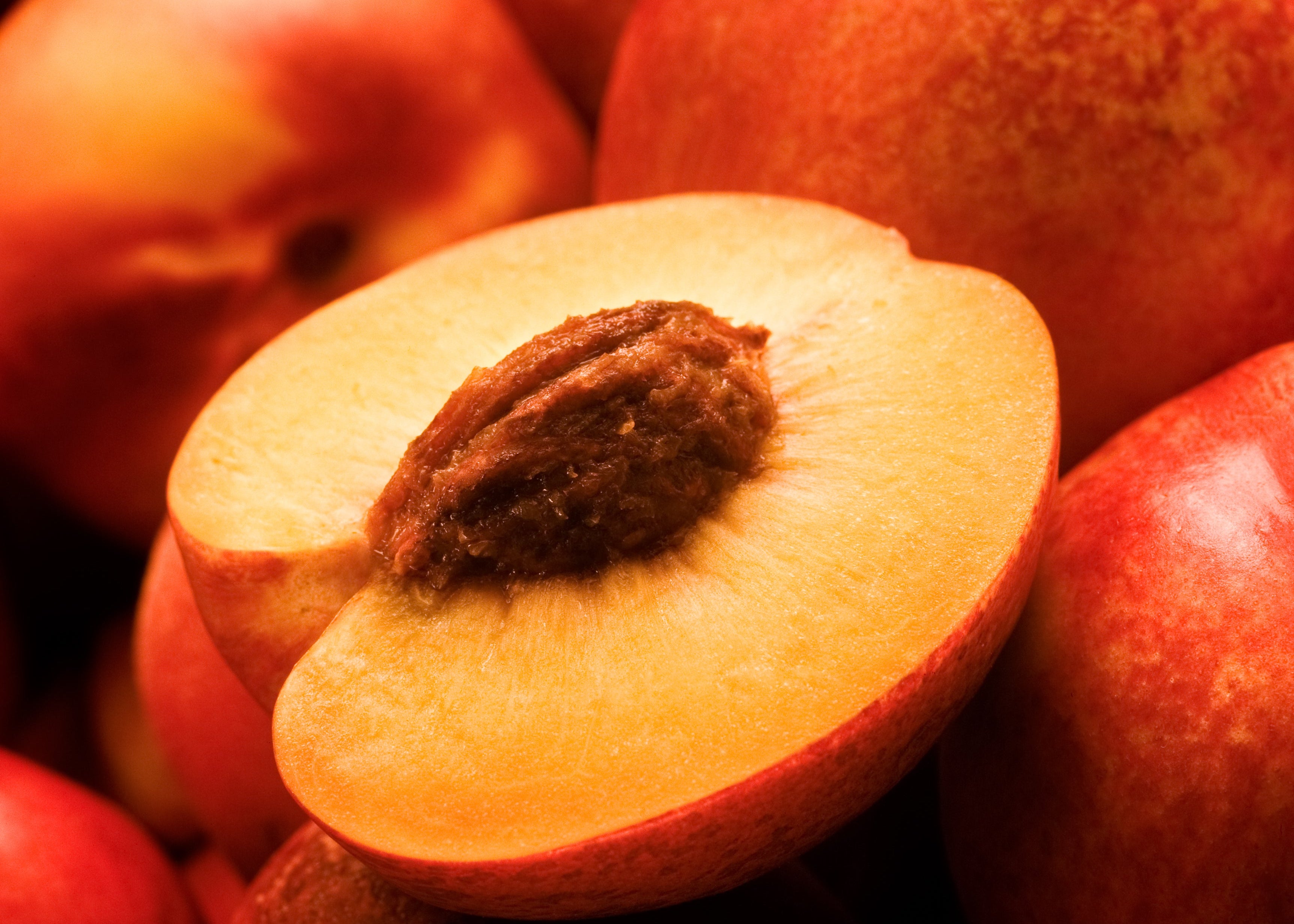 aufgeschnittener Pfirsich liegend auf anderen Pfirsichen