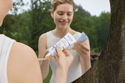 Frau gibt Zahnpasta auf Zahnbürste im Freien