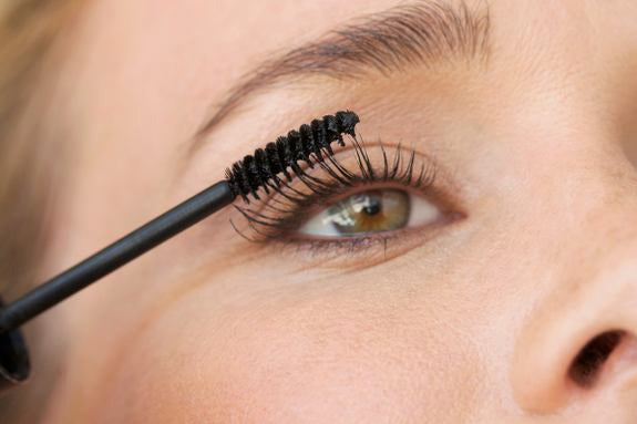 Nahaufnahme eines Auges beim Auftragen von Mascara mit Bürste