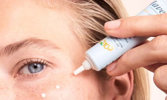 Frau trägt lavera Q10 Augencreme aus einer Tube um ihr Auge auf