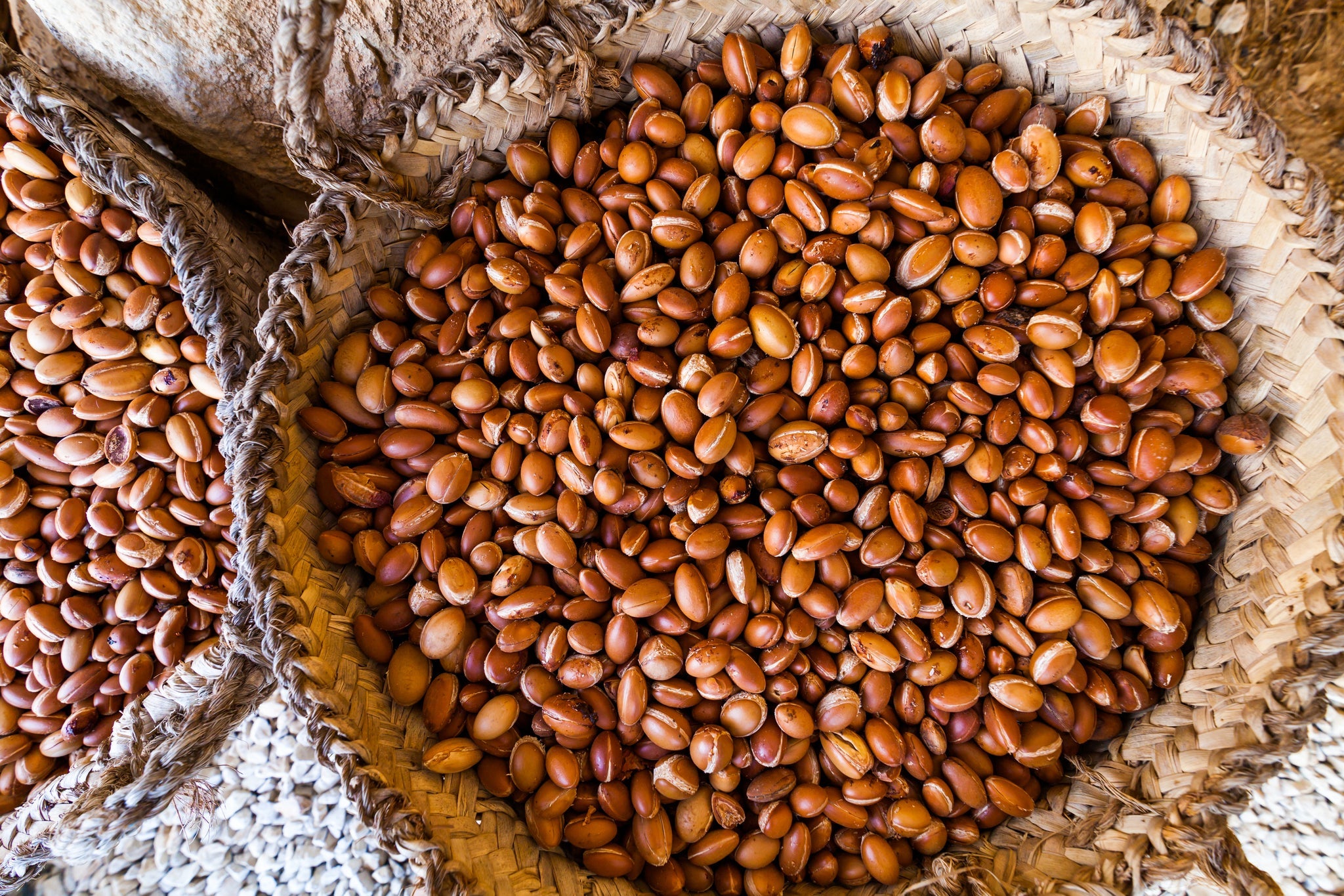 Geflochtene Körbe, gefüllt mit zahlreichen braunen Argan-Kernen