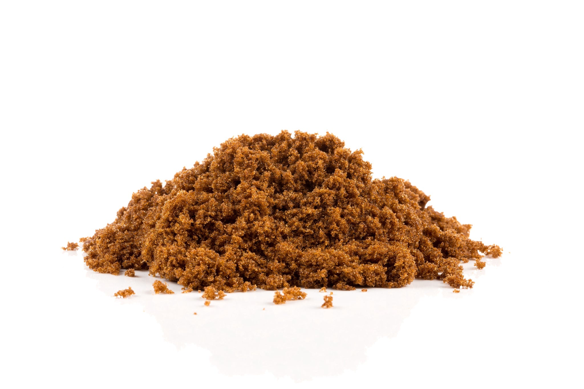Häufchen von lockerem, feuchtem braunem Zucker auf weißem Hintergrund.