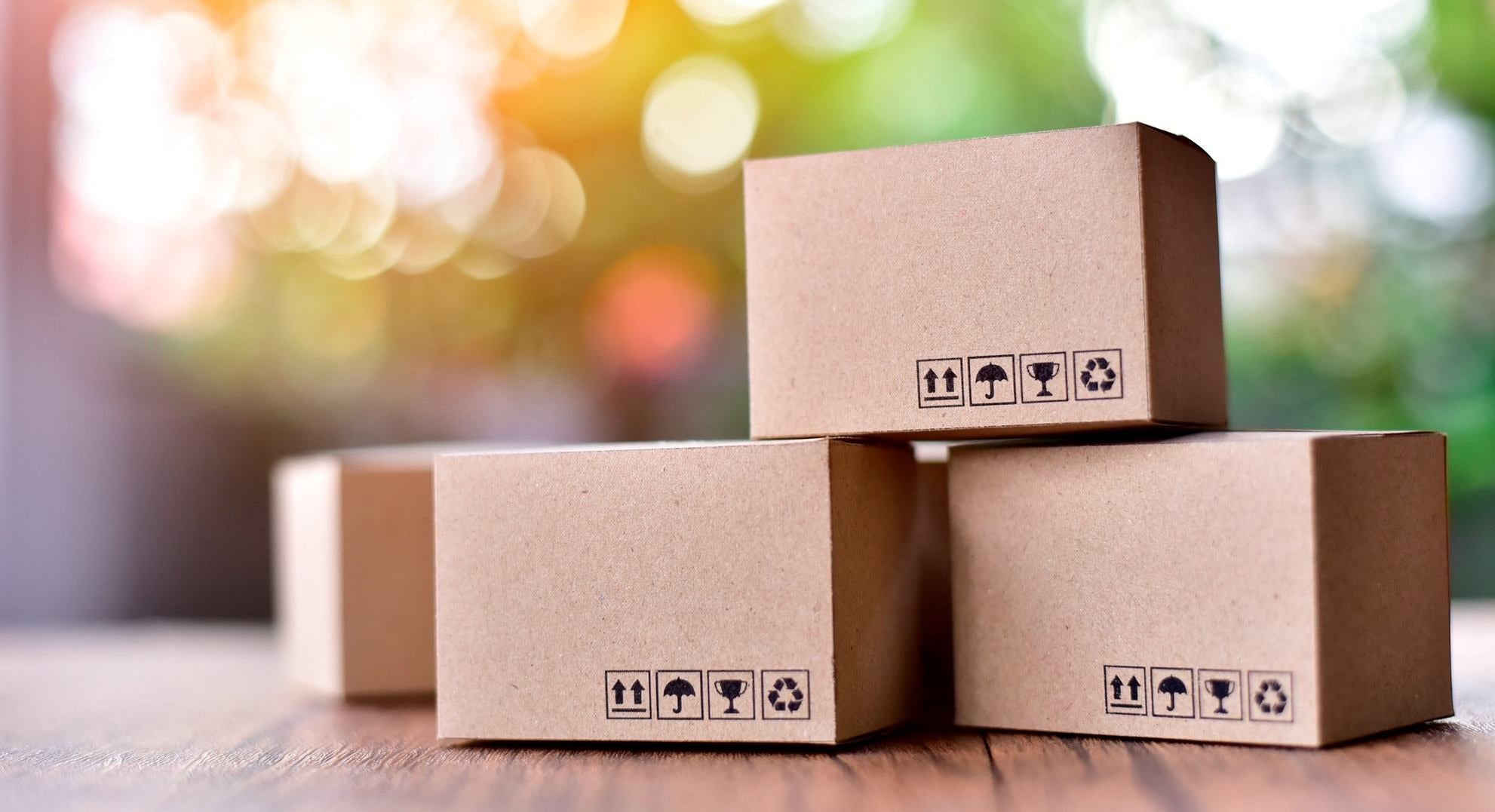 Stapel Kartons mit Versand-Symbolen auf Holztisch, Paketversand